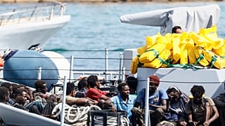 مهاجرون تم إنقاذهم يجلسون في قارب تابع للشرطة المالية الإيطالية قبل النزول في ميناء جزيرة لامبيدوسا، إيطاليا، الاثنين 18 سبتمبر 2023.