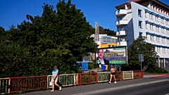 People pass an election billboard for the far-right Kotlebovci party in Banska Bystrica. The billboard reads: "We will save Slovakia from migrants".