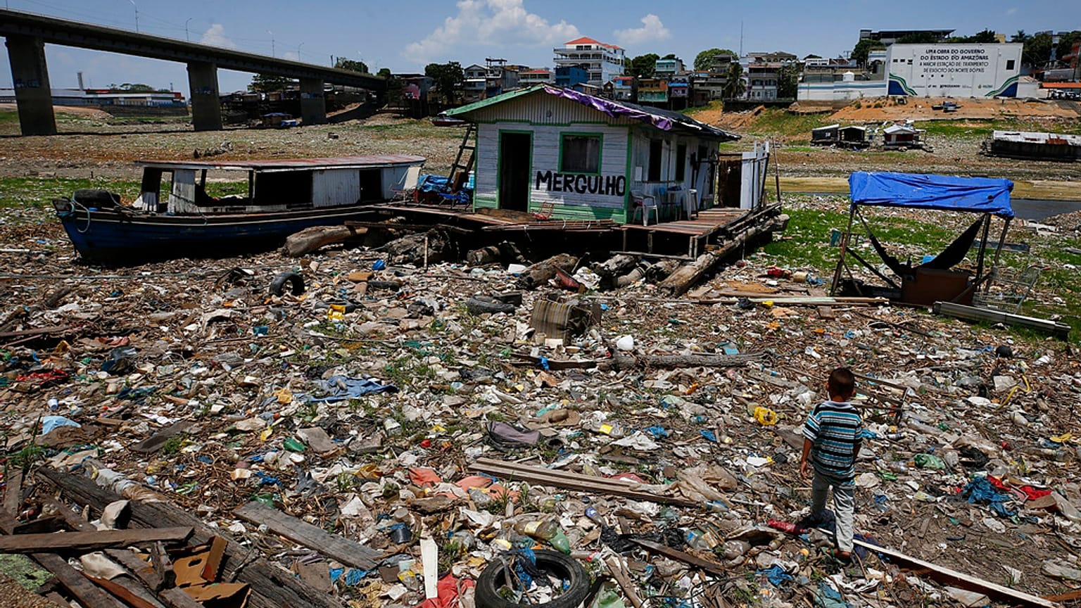 Unos niños caminan junto a una casa flotante varada en lo que solía ser la orilla del río Negro, en medio de una sequía en Manaos, Brasil.