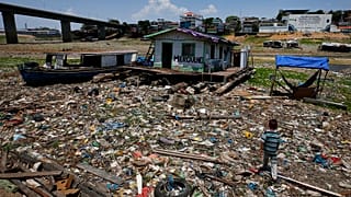 Unos niños caminan junto a una casa flotante varada en lo que solía ser la orilla del río Negro, en medio de una sequía en Manaos, Brasil.