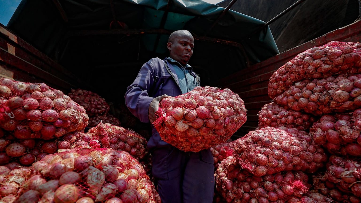 Timothy Kinyua unloads sacks of onions from Ethiopia at an open market in Nairobi, Kenya, 12 September, 2023.