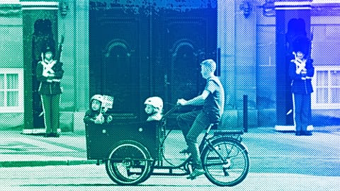 A cyclist rides a cargo bike with children in front of The Royal Life Guards at the Amalienborg Castle in Copenhagen, June 2023
