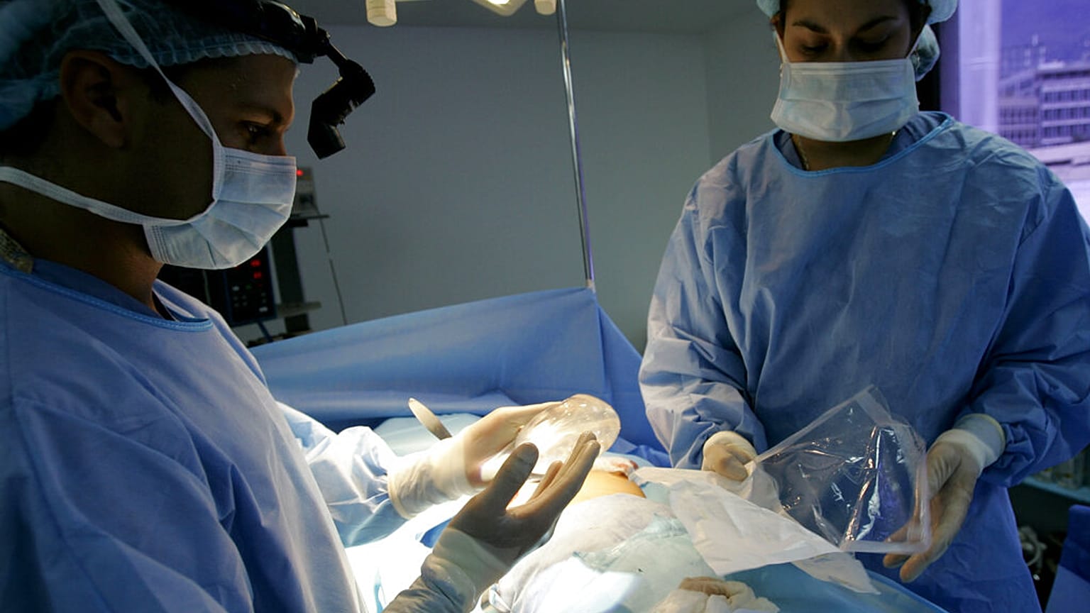 جراح التجميل الدكتور إسياس بيلو يحمل ثديًا من السيليكون أثناء جراحة زراعة الثدي في كاراكاس، فنزويلا، 21 سبتمبر، 2005.