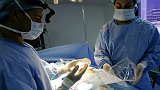 جراح التجميل الدكتور إسياس بيلو يحمل ثديًا من السيليكون أثناء جراحة زراعة الثدي في كاراكاس، فنزويلا، 21 سبتمبر، 2005.