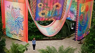 A garden employee poses for a picture near artwork entitled 'House of Spirits' by US artist Jeffrey Gibson, during a photocall for Kew Gardens' 'Queer Nature' 