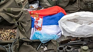 A Serbian flag is displayed along weapons and military equipment seized during the Kosovo police operation in the village of Banjska displayed in police camp in Kosovo 25/9/23