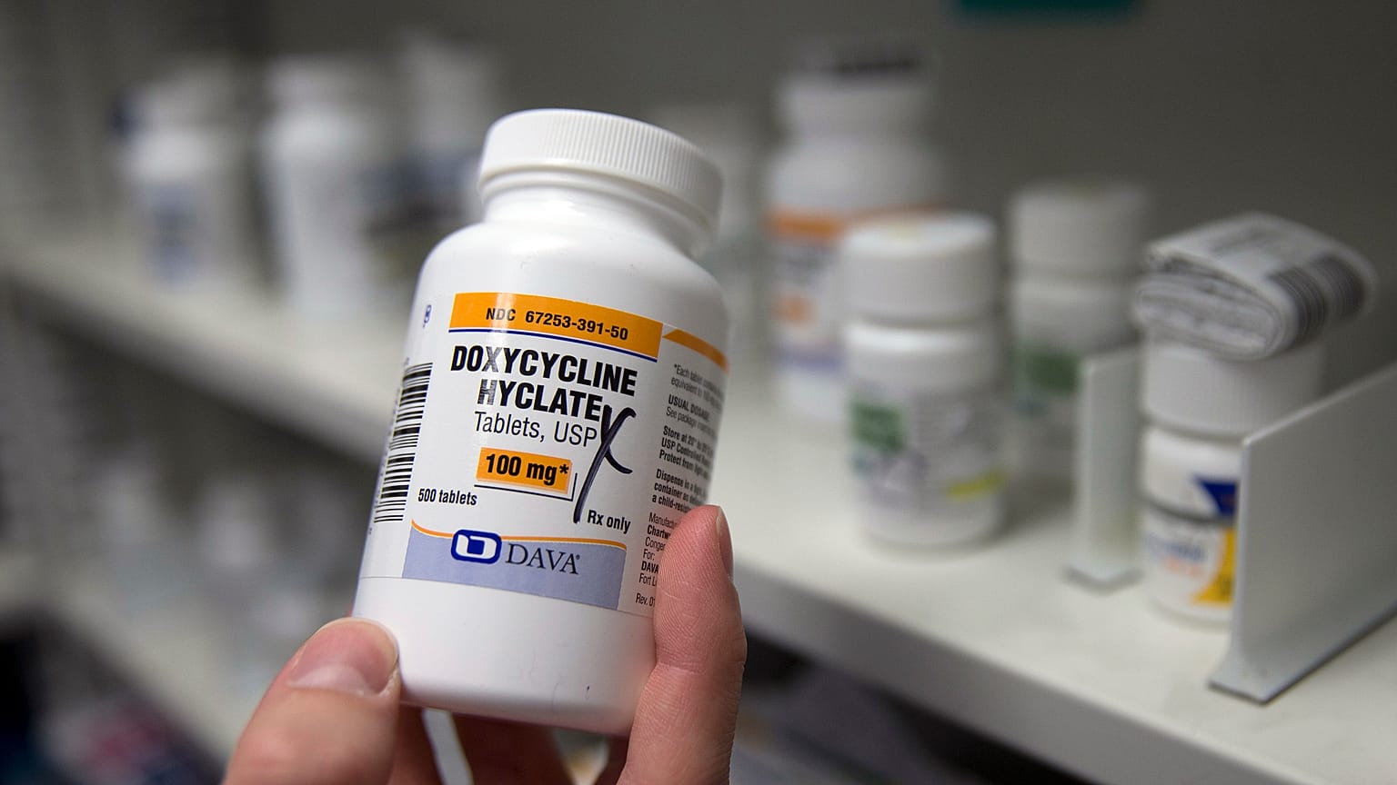 FILE - A pharmacist holds a bottle of the antibiotic doxycycline hyclate