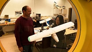 Image shows researchers from Delft University in the Netherlands displaying their drone prototype which saves energy by mimicking birdflight.