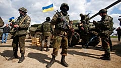 FILE - Ukrainian army troops receive ammunition, with a Ukrainian flag in the background, in a field on the outskirts of Izyum, Eastern Ukraine, Tuesday, April 15, 2014.