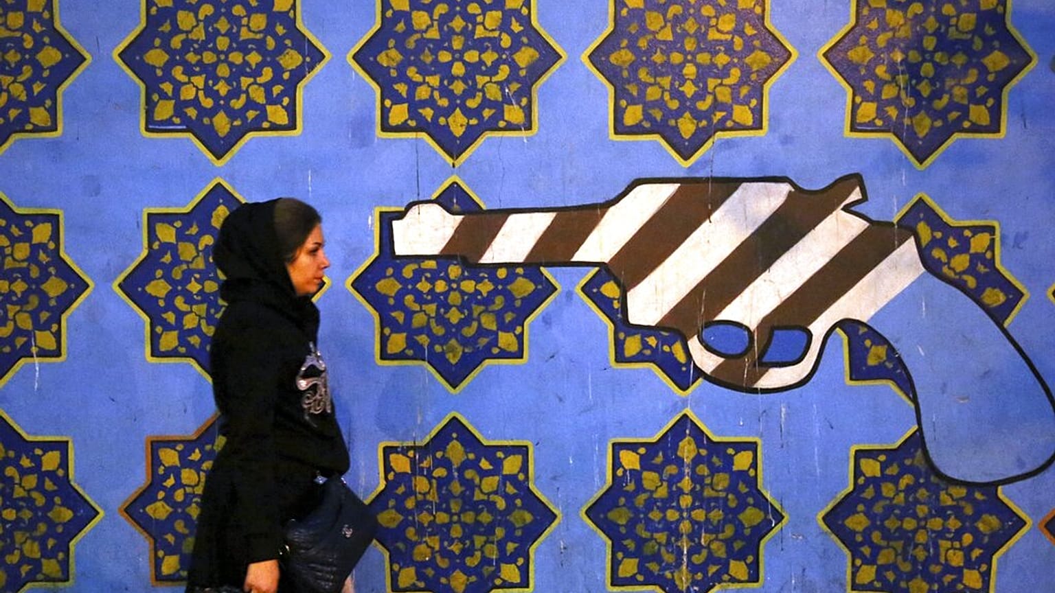 DOSSIER - Une femme iranienne passe devant une peinture murale anti-américaine, peinte sur le mur de l'ancienne ambassade des États-Unis, à Téhéran, en Iran, le samedi 2 novembre 2013.