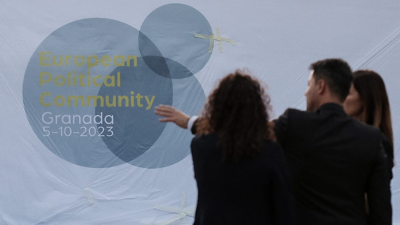 Persone in piedi davanti al logo del Vertice politico europeo, alla vigilia del vertice della Comunità politica europea a Granada, nel sud della Spagna, il 4 ottobre 2023\.