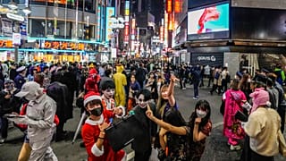 Halloween goers in costumes pose for pictures as thousands gather in Shibuya district in 2021.