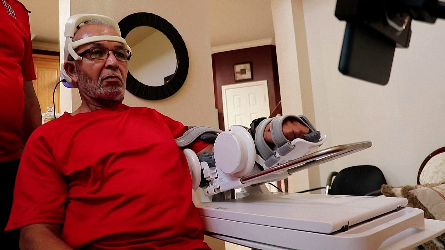 Image shows Oswald Reedus, a stoke survivor, trialling a new brain-reading headset that could help him recover the use of his limb.