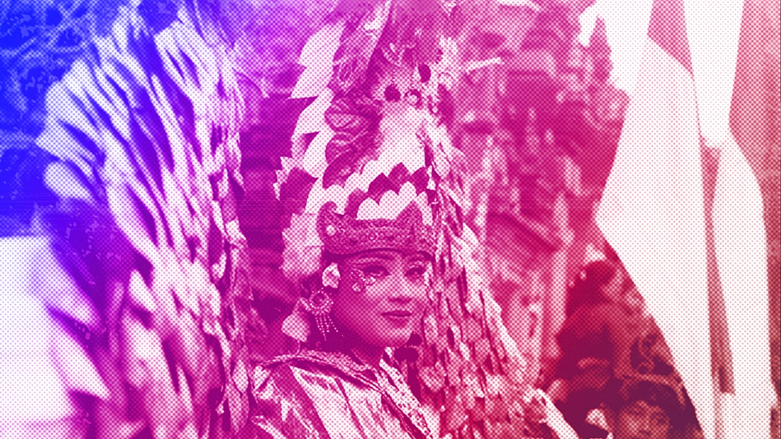 A woman in a costume stands next to Indonesia national flags during an Independence Day celebration parade in Ubud, Bali, August 2022