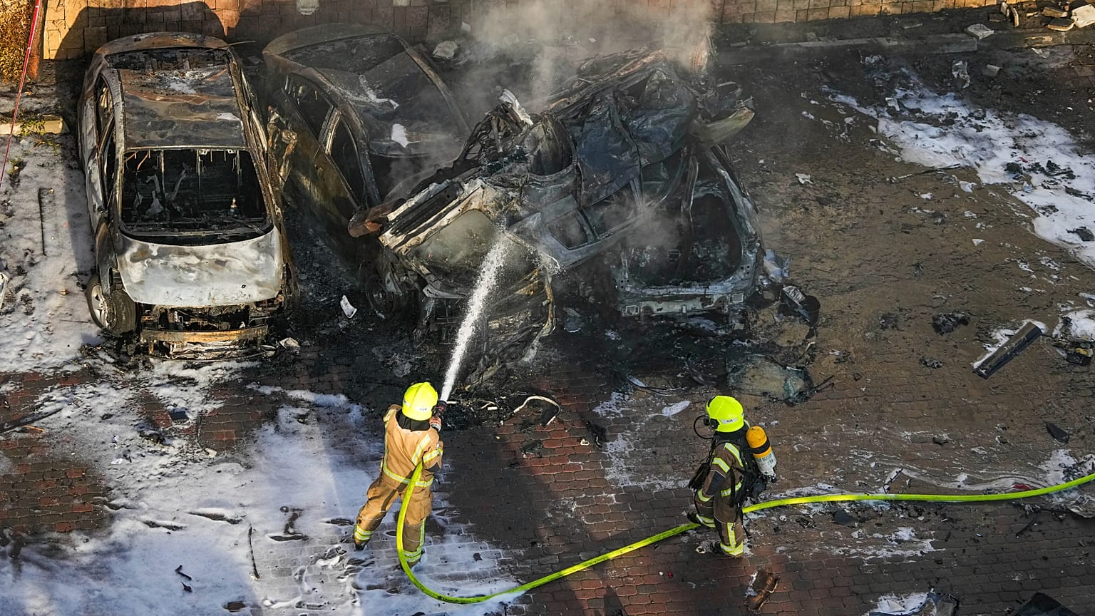 Israelische Feuerwehrleute löschen ein Feuer, nachdem eine aus dem Gazastreifen abgefeuerte Rakete auf einem Parkplatz in Aschkelon, Südisrael, eingeschlagen ist.