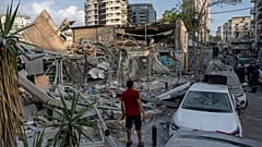 Des Israéliens inspectent les décombres d'un bâtiment après qu'il ait été touché par une roquette tirée depuis la bande de Gaza, à Tel Aviv, Israël, dimanche 8 octobre 2023.