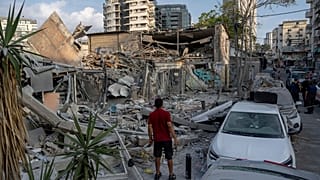 Des Israéliens inspectent les décombres d'un bâtiment après qu'il ait été touché par une roquette tirée depuis la bande de Gaza, à Tel Aviv, Israël, dimanche 8 octobre 2023.
