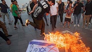 Iraquianos queimam bandeiras de Israel durante uma manifestação realizada no centro de Bagdade em apoio aos palestinianos, no sábado