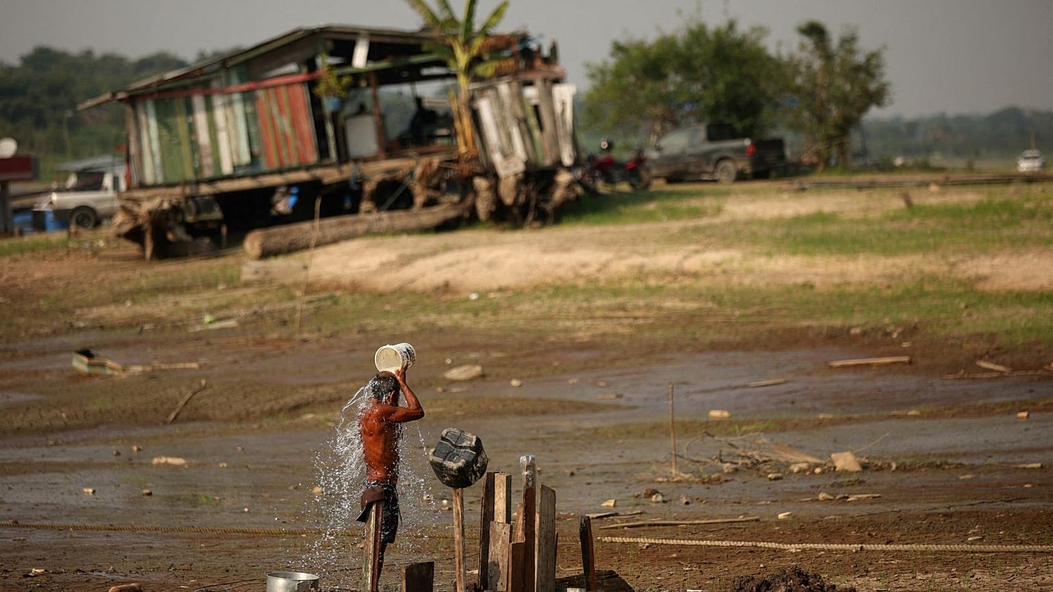 Fisherman Raimundo da Silva do Carmo, 67, baths with water from a well on Puraquequara Lake, which has been hard-hit by drought, in Manaus, Brazil, 6 October 2023.