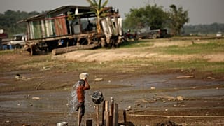 Fisherman Raimundo da Silva do Carmo, 67, baths with water from a well on Puraquequara Lake, which has been hard-hit by drought, in Manaus, Brazil, 6 October 2023.
