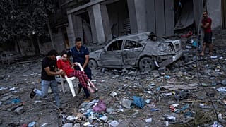 Palestinianos caminham nas ruínas de Gaza, após ataques aéreos israelitas