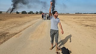 Des Palestiniens s'éloignent du kibboutz de Kfar Azza, en Israël, près de la barrière avec la bande de Gaza, le samedi 7 octobre 2023.