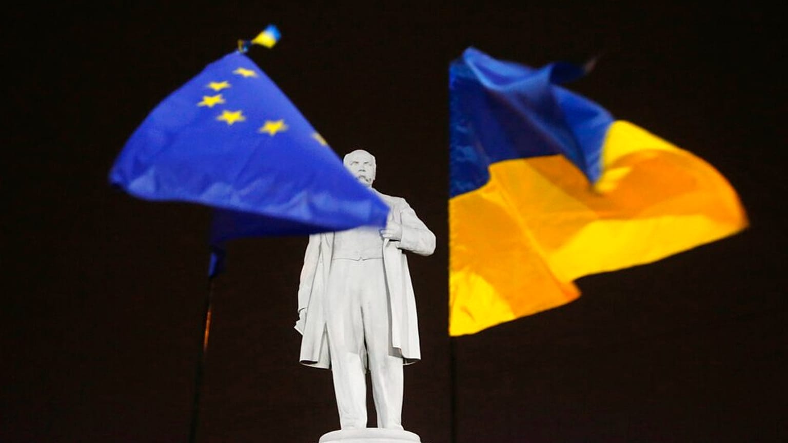 DOSSIER - Le 5 décembre 2013, des manifestants de l'opposition tiennent les drapeaux de l'UE et de l'Ukraine, à droite, autour d'un monument à la mémoire du poète ukrainien Taras Shevchenko dans le centre de Donetsk.
