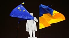 DATEI - Foto vom 5\. Dezember 2013: Oppositionelle Demonstranten halten die Flaggen der EU und der Ukraine (rechts) um ein Denkmal des ukrainischen Dichters Taras Schewtschenko in der Innenstadt von Donezk.