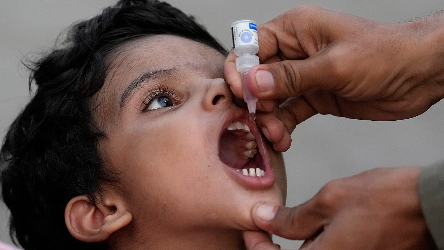 A health worker administers a polio vaccine to a child at a railway station in Karachi, Pakistan, September 2023