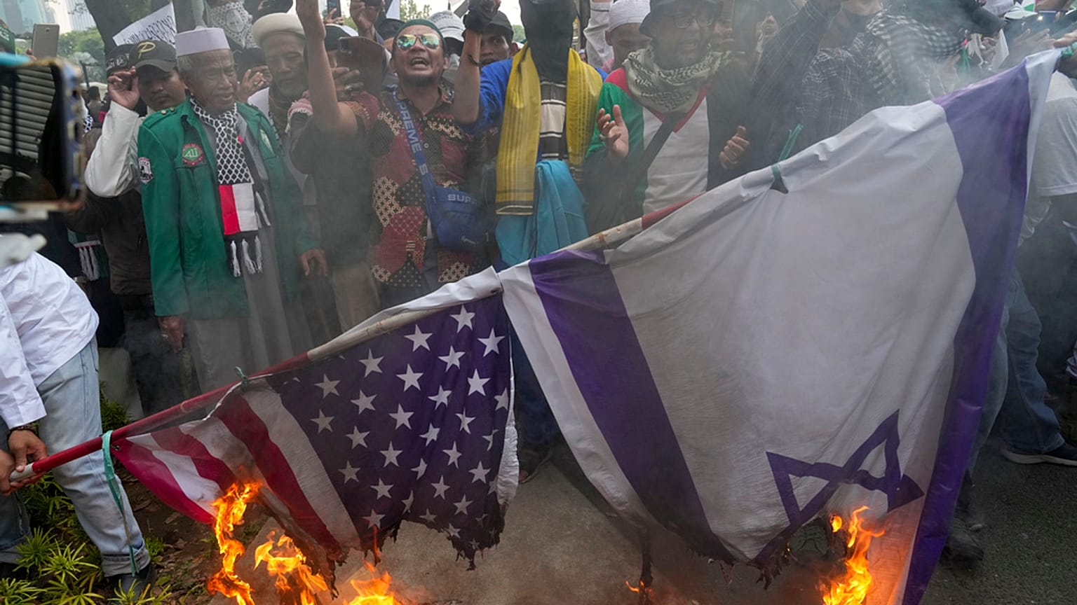 Manifestantes muçulmanos queimam bandeiras dos EUA e de Israel, à porta da embaixada norte-americana em Jacarta, Indonésia