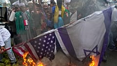 Manifestantes muçulmanos queimam bandeiras dos EUA e de Israel, à porta da embaixada norte-americana em Jacarta, Indonésia