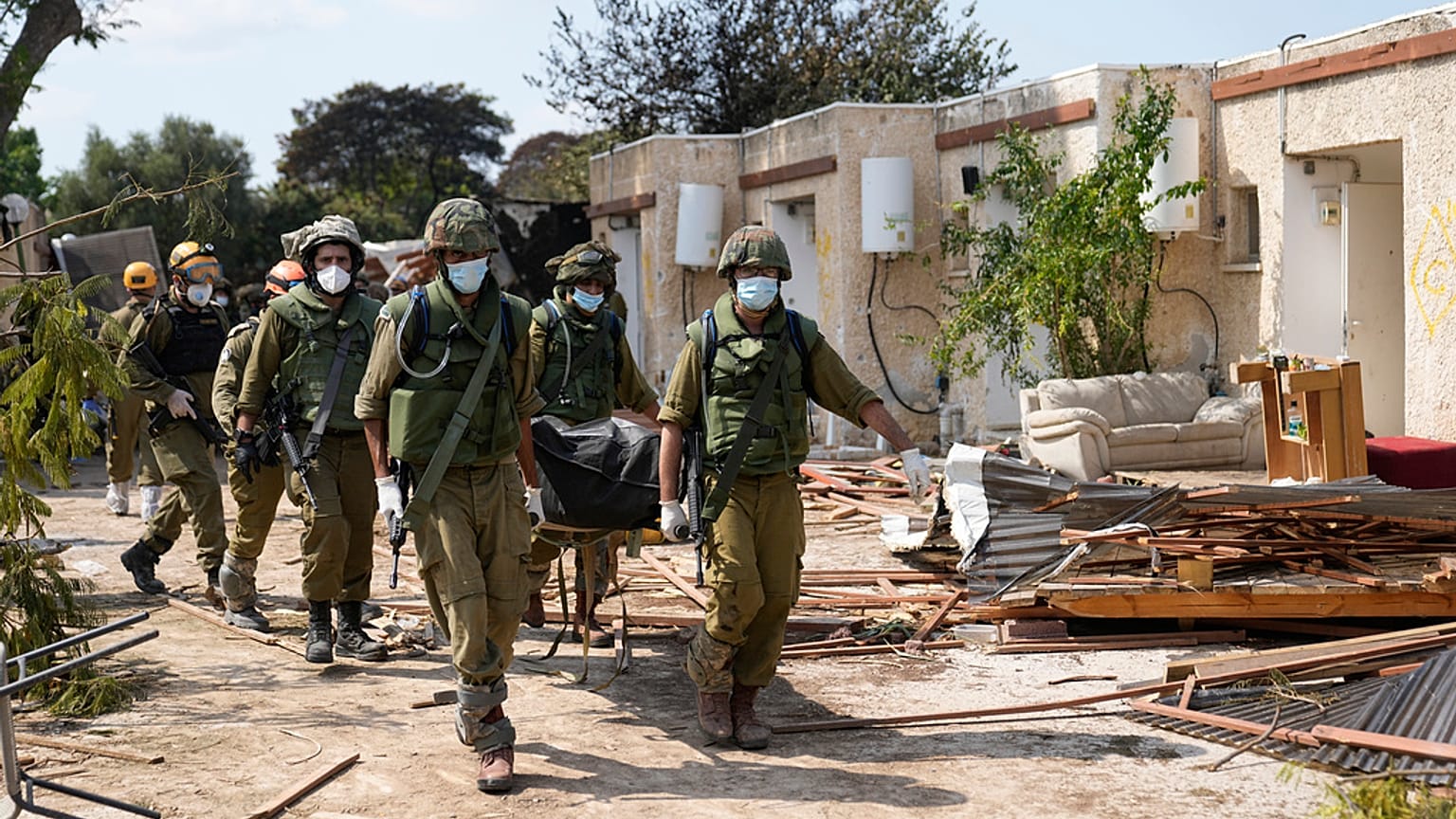 İsrail askerleri, Hamas saldırısında ölen bir kişinin cesedini taşırken 