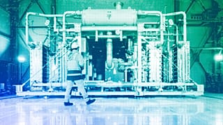 A worker walks in front of a electrolyzer for the production of green hydrogen in Oberhausen, May 2023