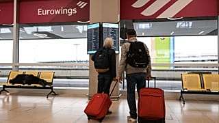 Travellers inspect a screen with flight details at Cologne-Bonn Airport, Germany, April 2023.