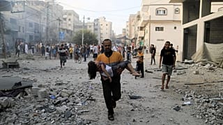 A Palestinian carrying a child runs following an Israeli strike in the southern Gaza Strip on Saturday as fighting between Israel and Hamas continues for an eighth day