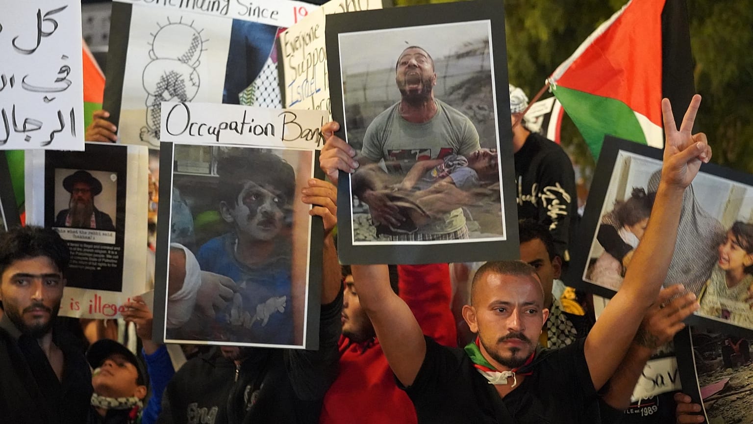 People carry pictures and wave Palestinian flags as they rally to express solidarity with Palestinians is the Gaza Strip, in Larnaca on October 15 2023