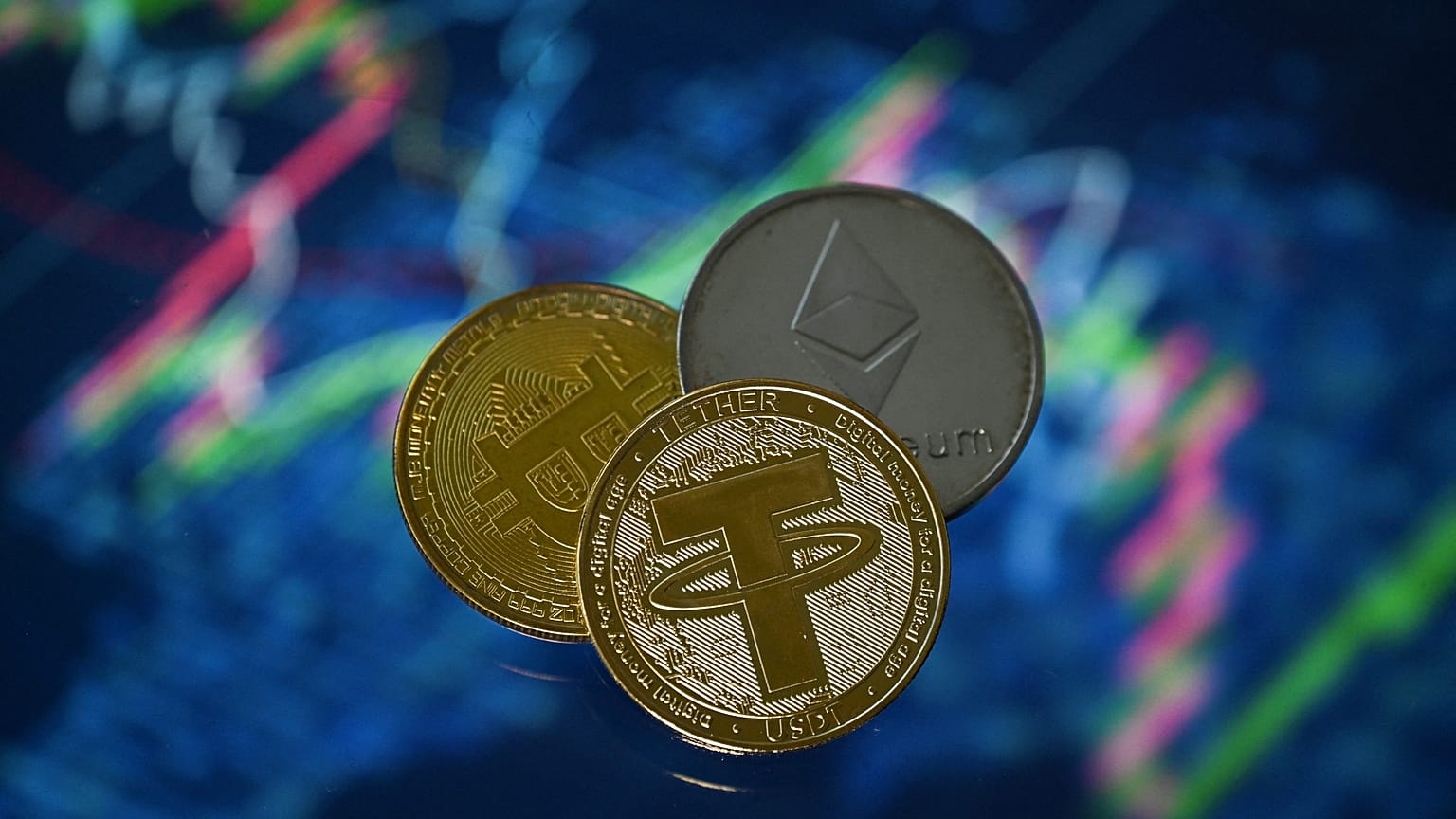An illustration picture taken in London on May 8, 2022, shows gold plated souvenir cryptocurrency Tether (USDT), Bitcoin and Etherium coins.