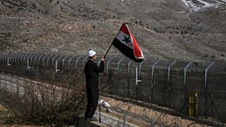 صبي من السكان الدروز في مجدل شمس بالجولان المحتل يلوح بعلم سوريا بالقرب من السياج الحدودي