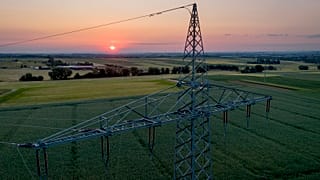 Una torre di trasmissione si erge su un campo alla periferia di Francoforte, in Germania, mentre il sole sorge il 6 giugno 2023\.