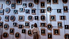 A woman stands in front of a wall with pictures of Slovenian authors in the Slovenian pavilion at the Book Fair in Frankfurt, Germany, Tuesday, Oct. 17, 2023.
