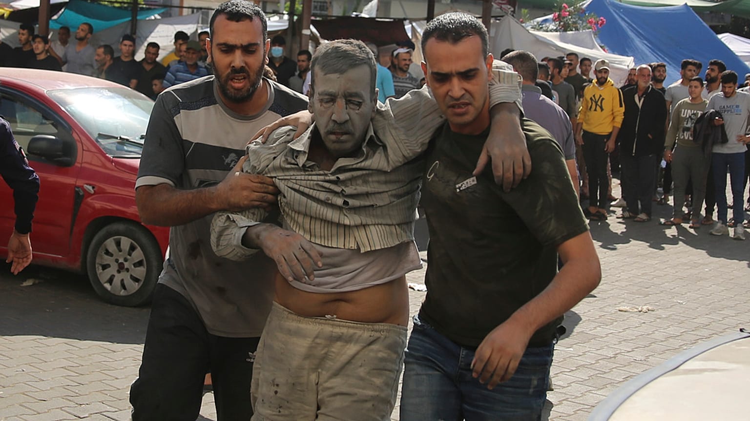 Dos personas trasladan a uno de los heridos en el hospital de Gaza