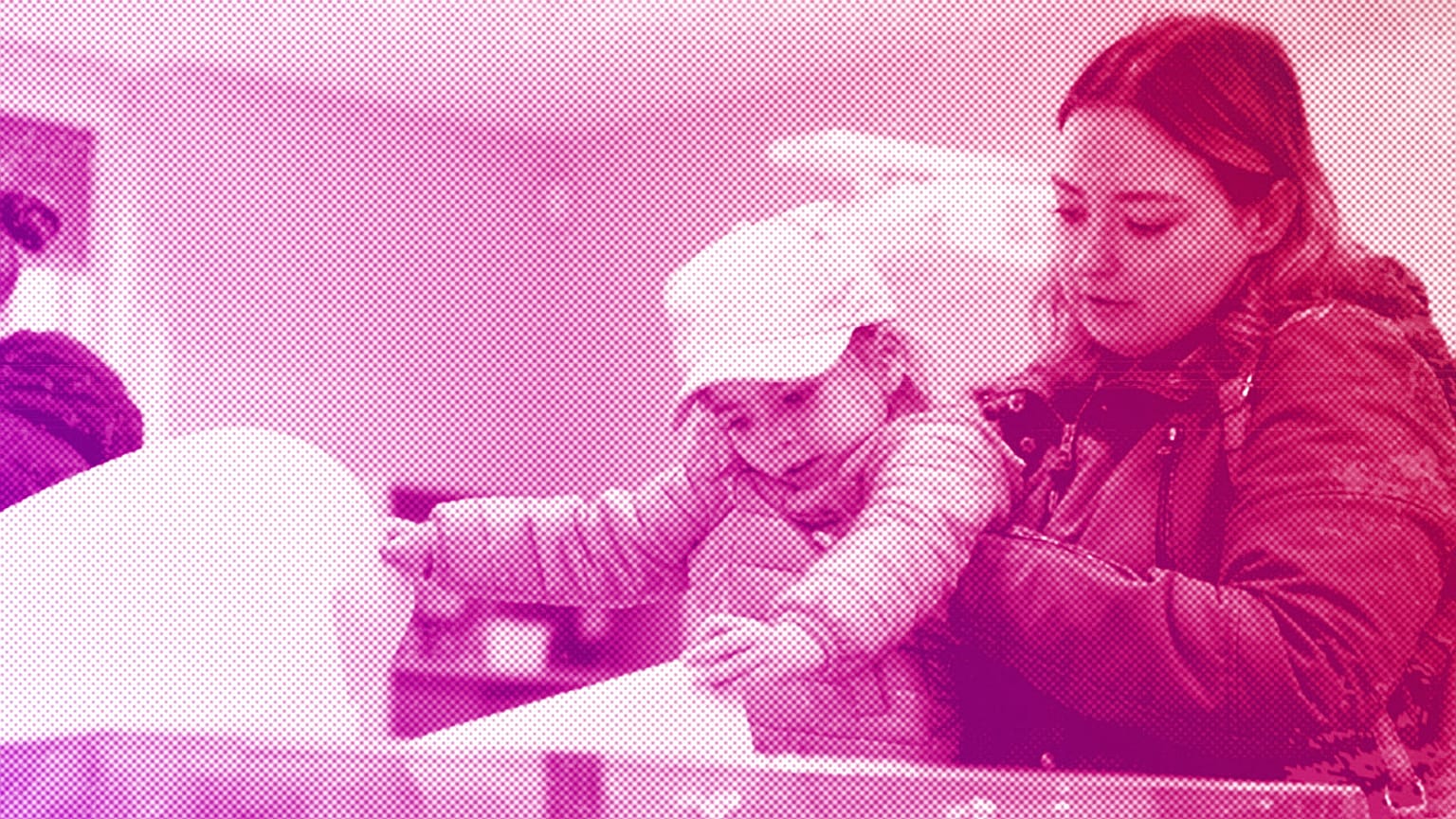 A woman holds a toddler to cast her ballot during parliamentary elections in Warsaw, October 2023