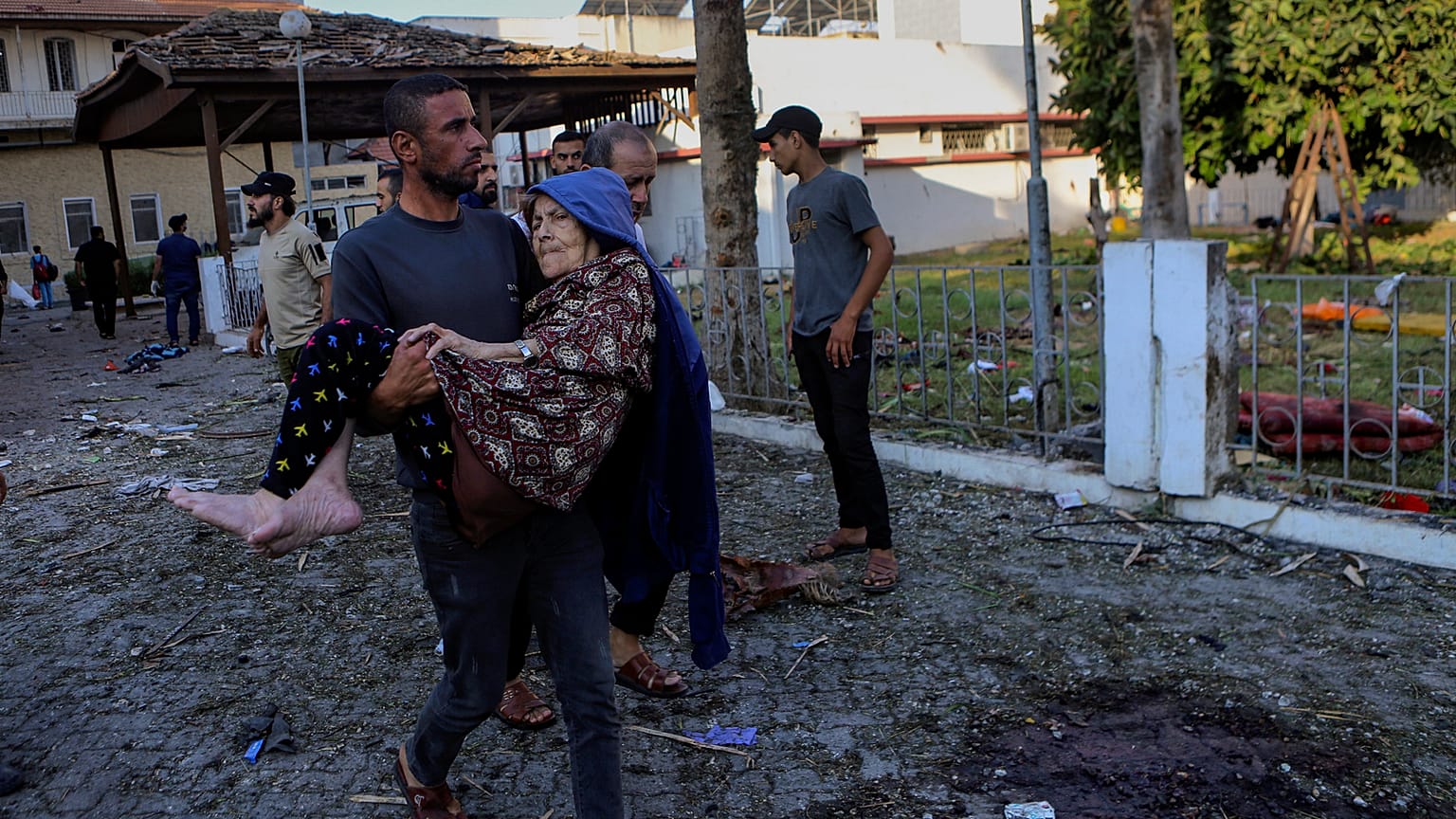 Un uomo palestinese trasporta una donna anziana davanti al luogo dell'esplosione mortale all'ospedale al-Ahli, a Gaza City, mercoledì 18 ottobre 2023\. 
