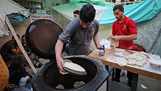 فلسطينيون يحضرون الخبز في كشك خارج مستشفى الشفاء في مدينة غزة في 16 أكتوبر 2023.