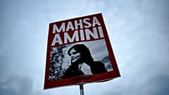 İran'da kıyafet kurallarına uymadığı iddiasıyla polis gözetemindeyken hayatını kaybeden Mahsa Amini'nin fotoğrafının bulunduğu döviz