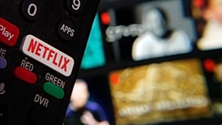 Le bouton Netflix d'une télécommande de télévision est juxtaposé à une page web de Netflix, en février 2023.