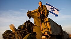An Israeli soldier sits atop of an armored vehicle at a staging area near Israel's border with Gaza, in southern Israel, 