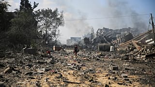 Um menino palestiniano caminha junto a edifícios destruídos pelo bombardeamento israelita em al-Zahra