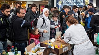 توزيع الطعام والشراب من قبل متطوعين على اللاجئين بعد وصولهم إلى محطة القطار في مالمو، السويد