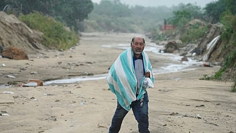 A man walks on the mud caused by hurricane Norma in San Jose del Cabo, Mexico, Saturday, Oct. 21, 2023. Norma